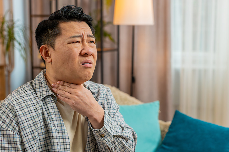 A man experiencing a sore throat as a result of thyroid