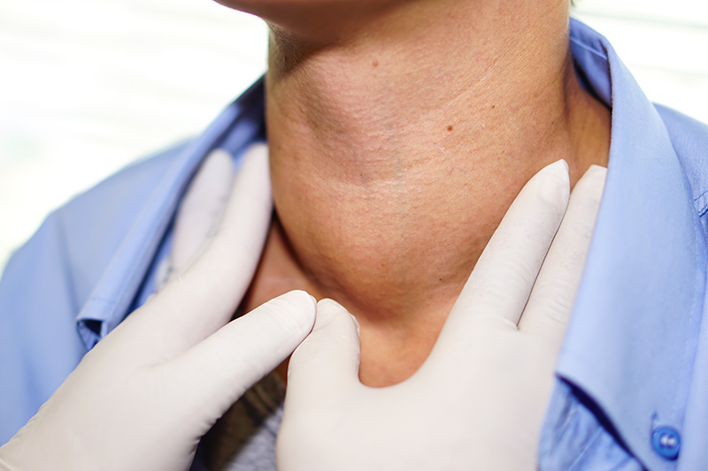 A doctor examining a swollen lump on a patient's neck